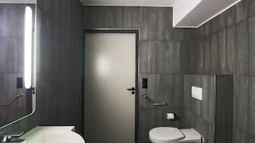 Een moderne badkamer met een witte wasbak, toilet en een deur met een matglazen paneel.