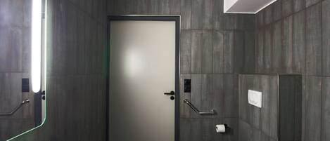 A modern bathroom with a white sink, a toilet, and a door with a frosted glass panel.