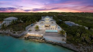 A large, two-story house with a swimming pool, surrounded by tropical vegetation and a clear view of the ocean. - Oceanfront mansion, heated infinity pool. 6 double rooms, 11 beds can sleep 18 (George Town)