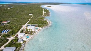 An aerial view of a coastal property with a swimming pool, a small building, and a clear view of the turquoise sea. - Oceanfront mansion, heated infinity pool. 6 double rooms, 11 beds can sleep 18 (George Town)