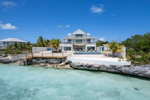 A two-story beachfront property with a pool, a deck, and a view of the ocean.