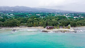 A coastal area with a beach, a small building, and a forested hill in the background. - Vista del Mar by Cocotel (Zamboanga)