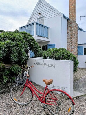 Una bicicleta roja estacionada frente a un edificio con un letrero que dice 'Sandpiper'.