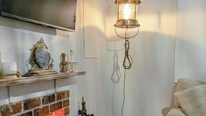 Un salon avec une cheminée, un téléviseur fixé au mur, une lanterne suspendue et un fauteuil confortable.