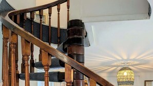 Un escalier en colimaçon avec des balustrades en bois et des marches recouvertes de moquette.