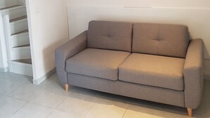 Una sala de estar moderna con un sofá gris, paredes blancas e iluminación empotrada en el techo.