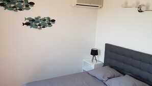 Un dormitorio con cama, aire acondicionado de pared y una mesita de noche con lámpara.