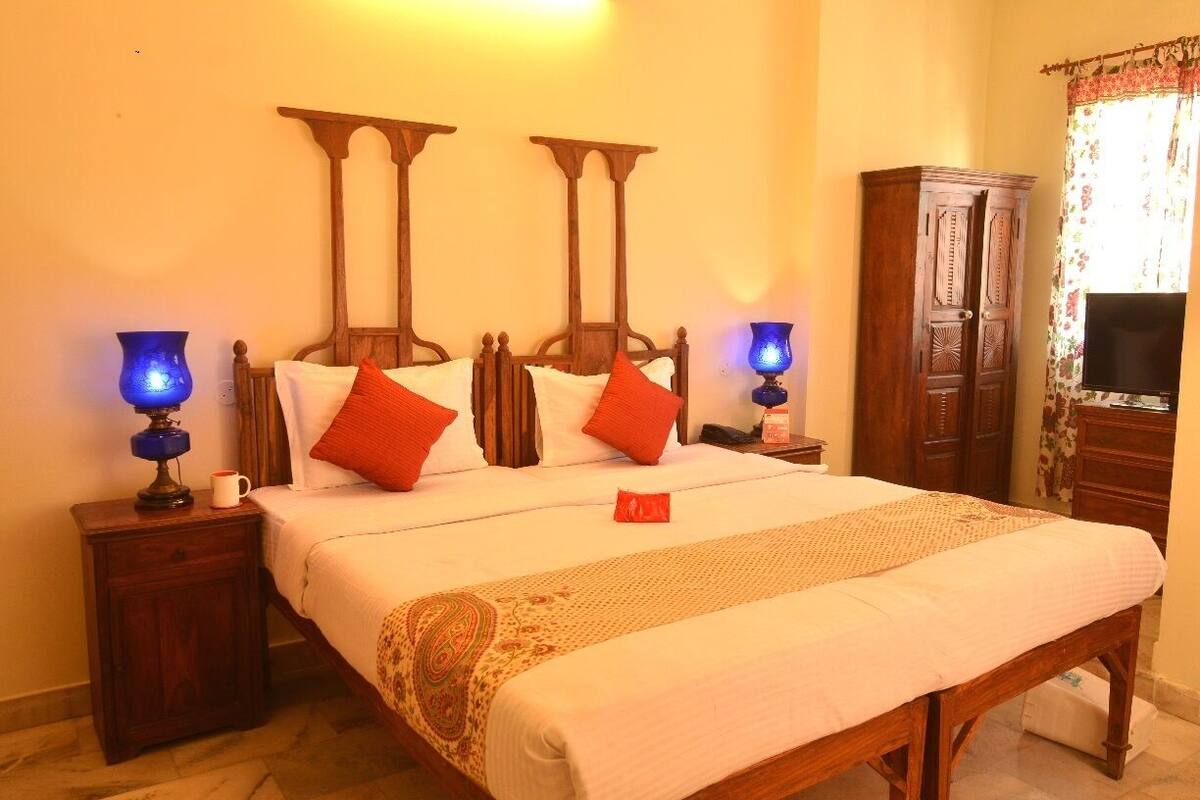 A bed with a wooden headboard, two bedside tables with lamps, a television, and a wardrobe.