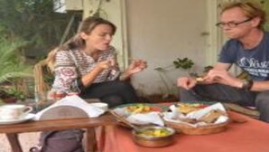 Un comedor con una mesa dispuesta para dos personas, destacando una cesta de pan y un bol de fruta.