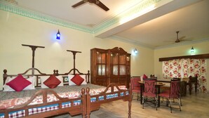 Una habitación con una cama de madera, una mesa de comedor con sillas, un ventilador de techo y un armario.
