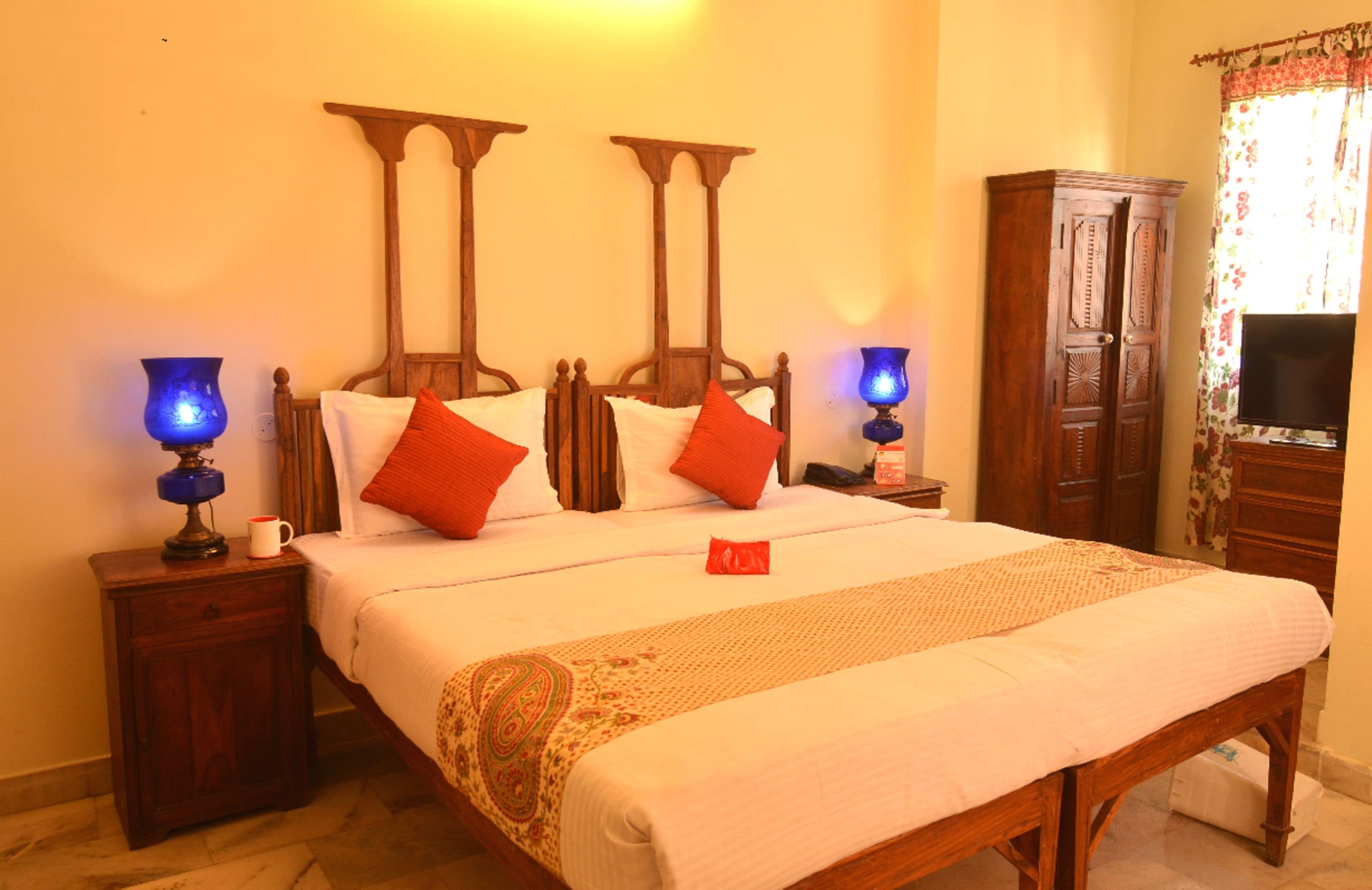 Une chambre d’hôtel avec un grand lit, deux tables de chevet, une armoire et un téléviseur.