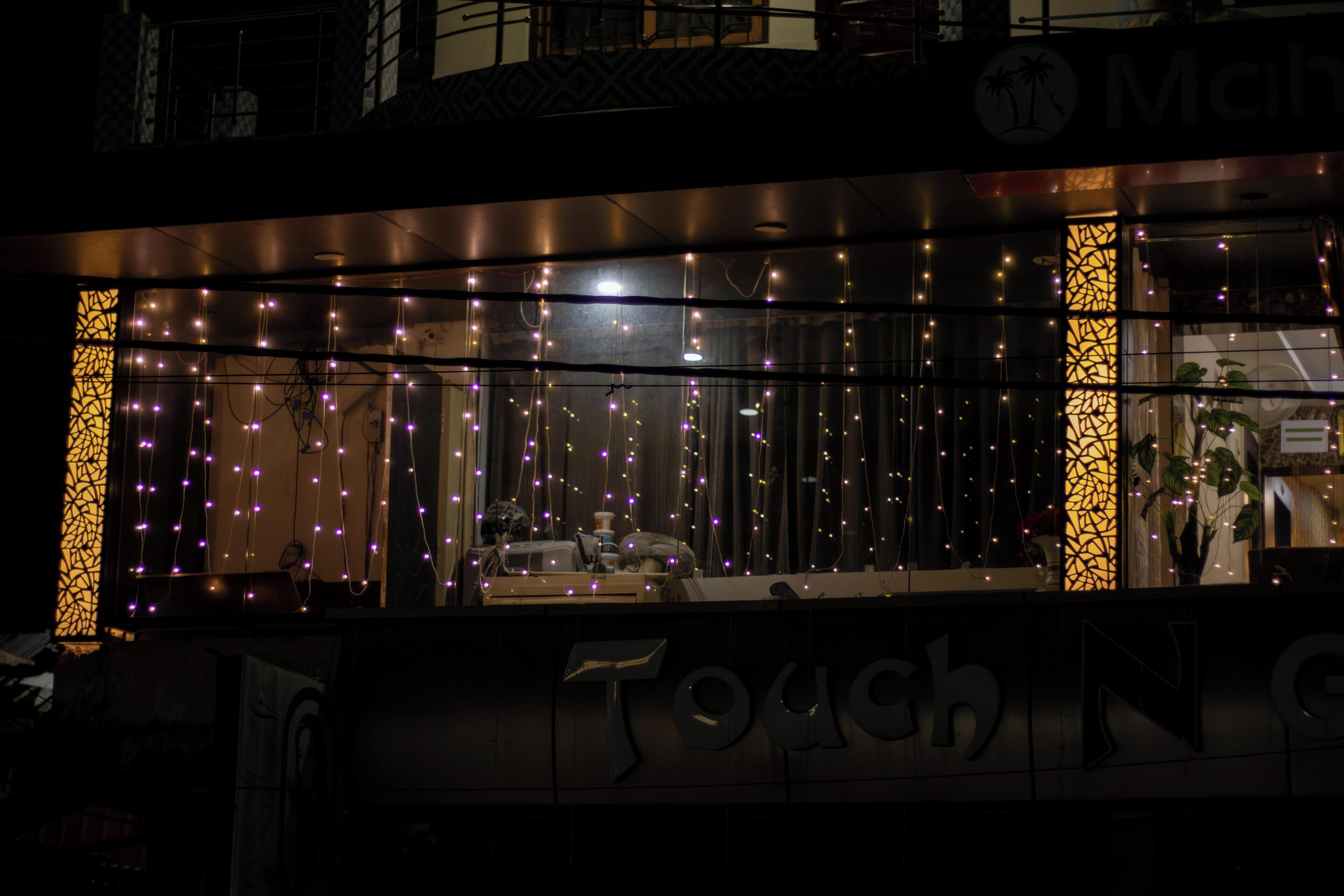 A hotel facade with illuminated string lights, a large glass window, and a sign reading "Touch N' Go".