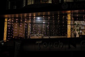 A hotel facade with illuminated string lights, a large glass window, and a sign reading "Touch N' Go". - Mahira Residency (Port Blair)