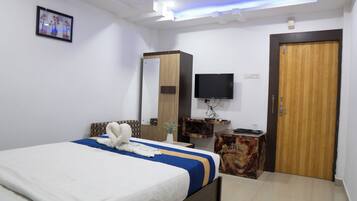 Una habitación de hotel moderna con cama, televisión de pantalla plana, puerta de madera y una mesita con un florero.