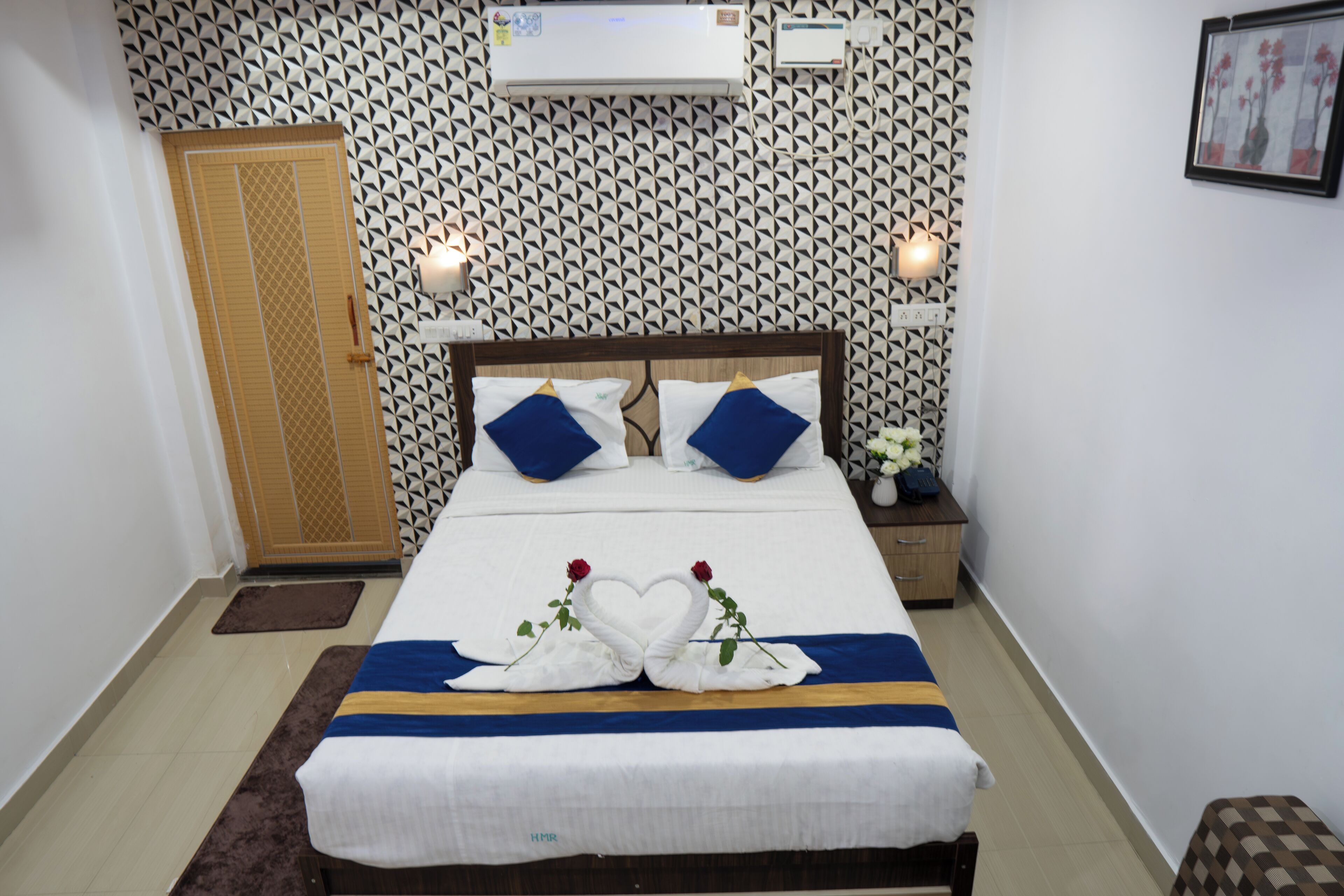 Un lit bien fait, avec une couvre-lit bleue et blanche, deux oreillers et un cygne décoratif fait de serviettes.