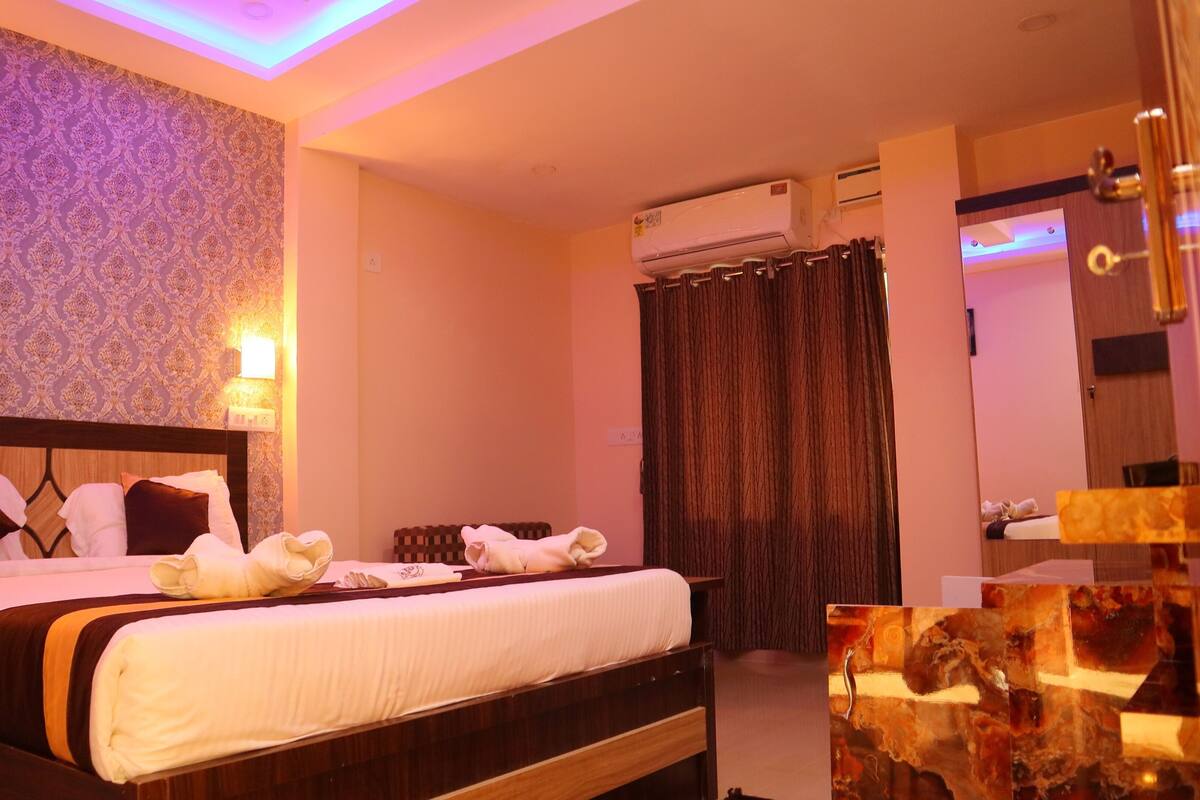 Une chambre d’hôtel avec un lit, un climatiseur fixé au mur et un miroir.