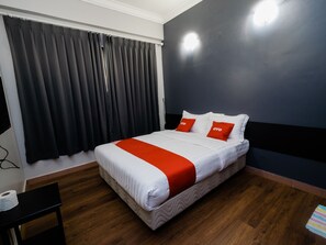 Una cama bien tendida con ropa de cama blanca y naranja, una pared azul oscuro y un suelo de madera.