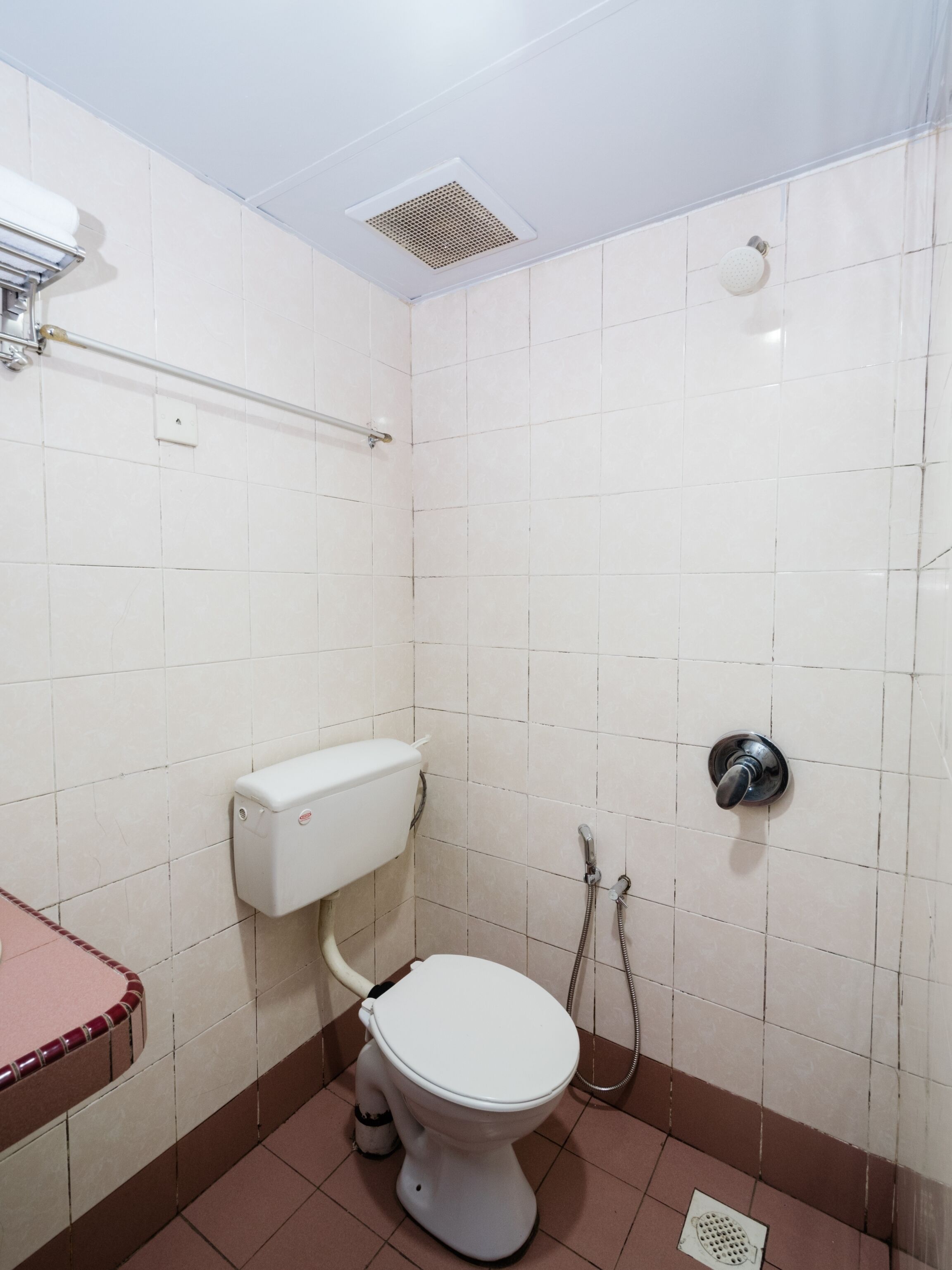 A small, tiled bathroom with a toilet, a shower, and a sink.
