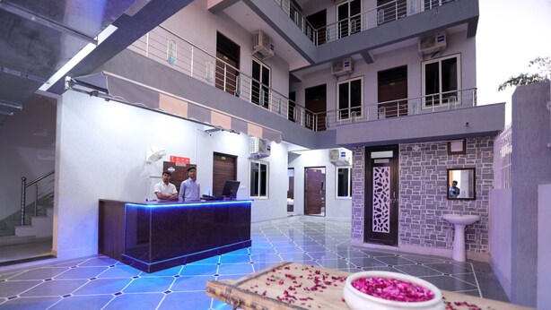 A hotel lobby with a reception desk, a staircase, and a decorative table with flowers. - Ranbanka Hotel & Restaurant (Udaipur)