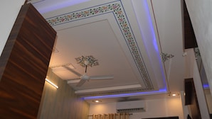 A room with a ceiling fan, decorative floral patterns, and a wooden accent wall. - Ranbanka Hotel & Restaurant (Udaipur)