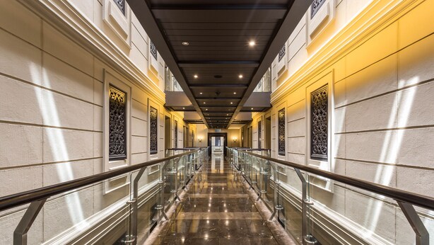 A long, well-lit hallway with marble floors and metal railings, leading to a door at the end. - Unit 613 Cape Royale Apartments (Cape Town)