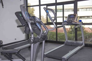 Dos máquinas de ejercicio en una sala con ventanas amplias.
