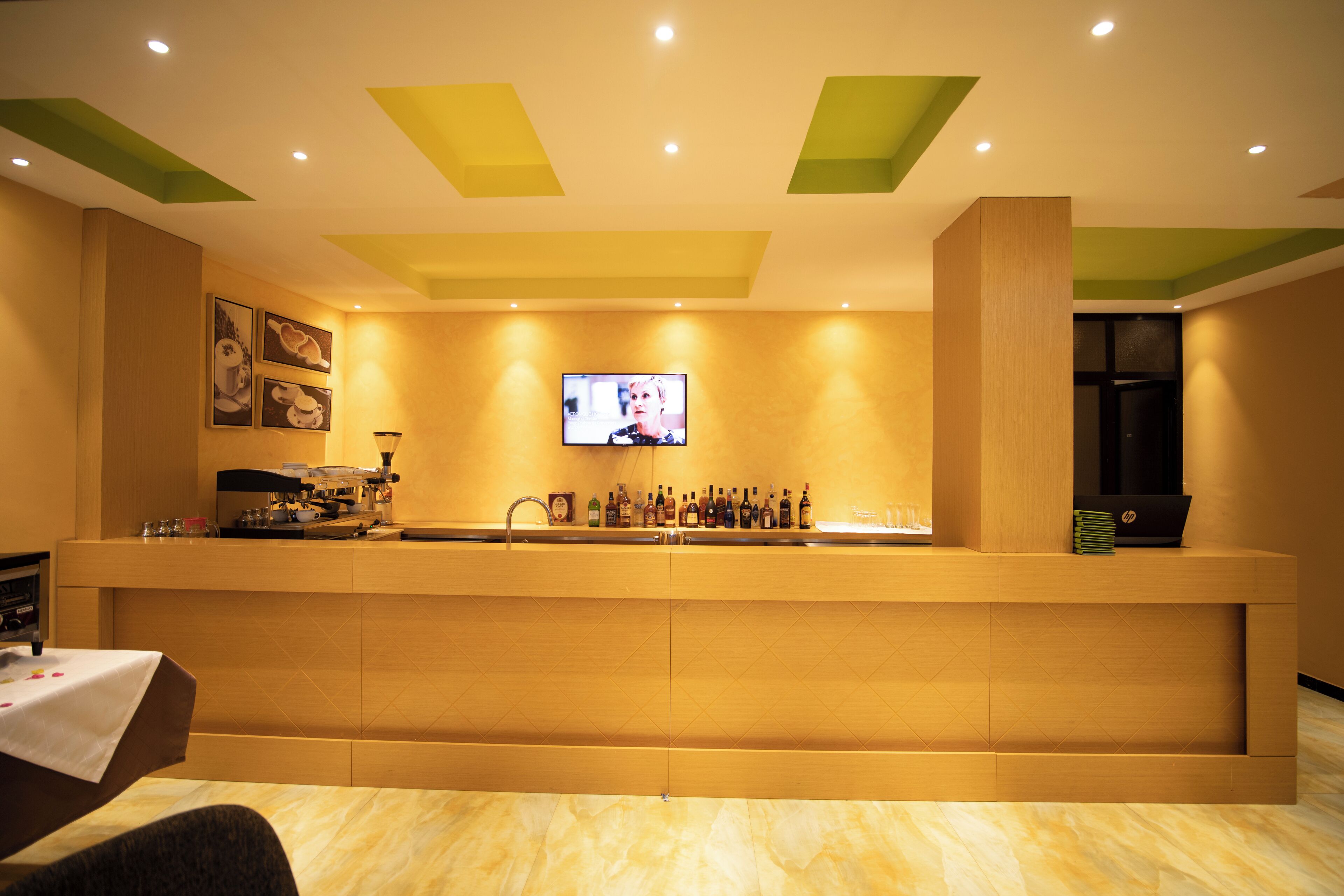 A reception area with a counter, a television mounted on the wall, and a coffee machine.