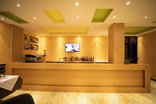 A reception area with a counter, a television mounted on the wall, and a coffee machine.
