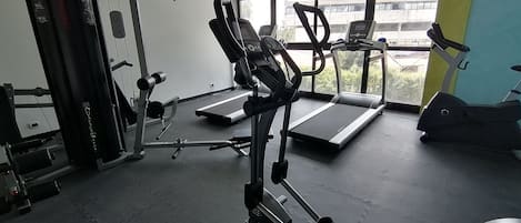 A gym with treadmills, weight machines, and a bench press.