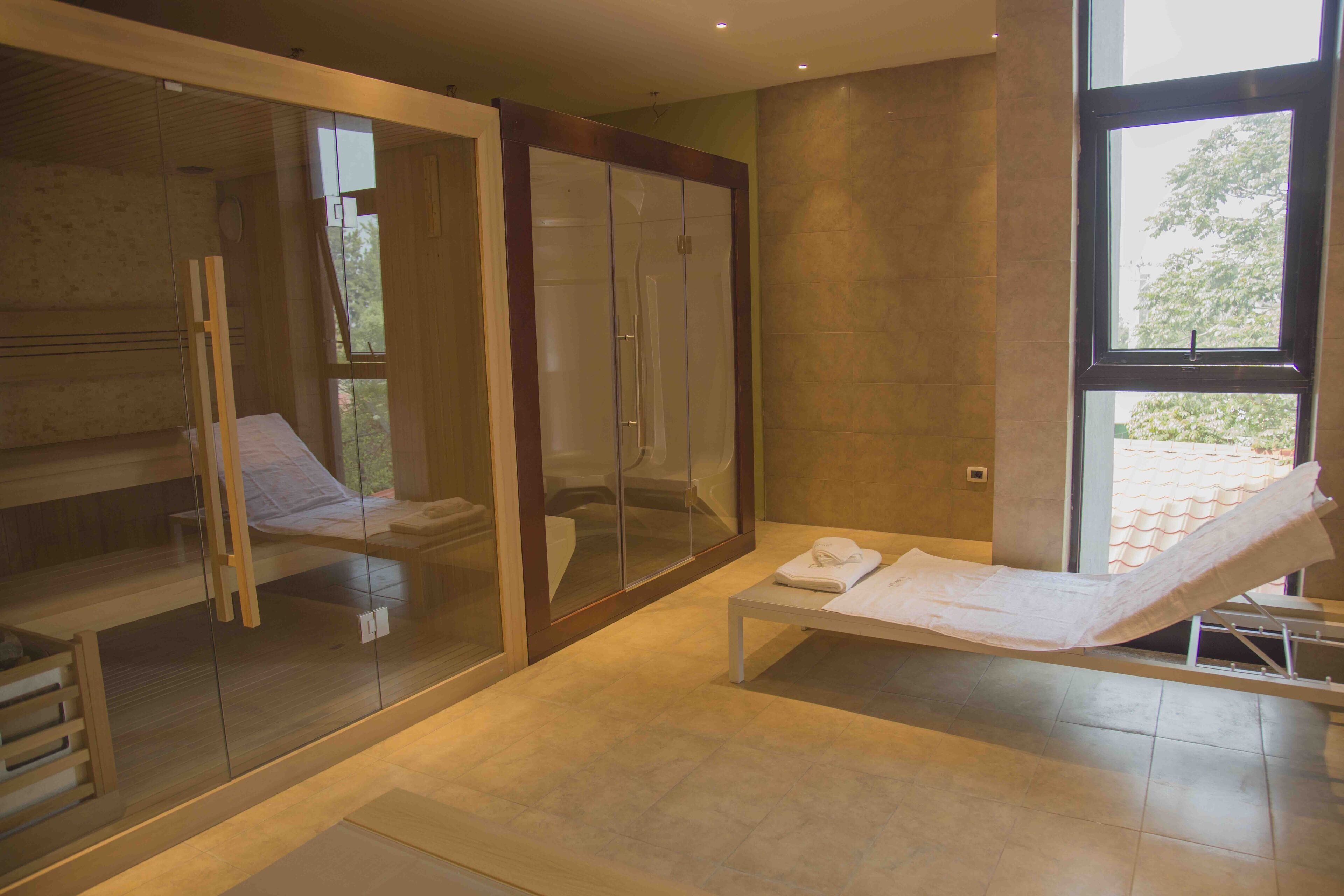 A spa room with a glass-enclosed shower, a massage table, and a wooden bench.