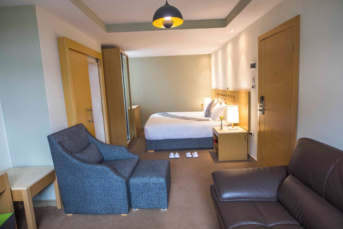 Une chambre d’hôtel avec un lit, un bureau, une chaise, un canapé et une lampe.