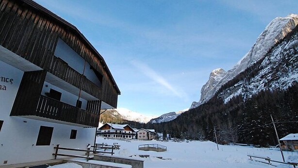 Paisaje nevado con un edificio moderno que presenta un techo curvo y fachada de madera.