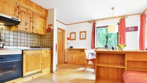 Una cocina acogedora de estilo rústico con armarios de madera, horno empotrado y comedor con mesa y sillas.