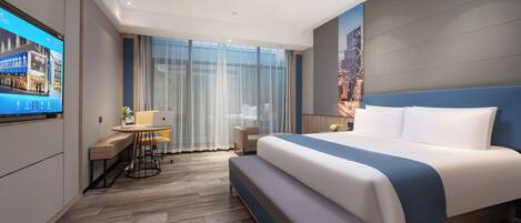 A modern hotel room with a large bed, a desk, and a TV displaying a cityscape.