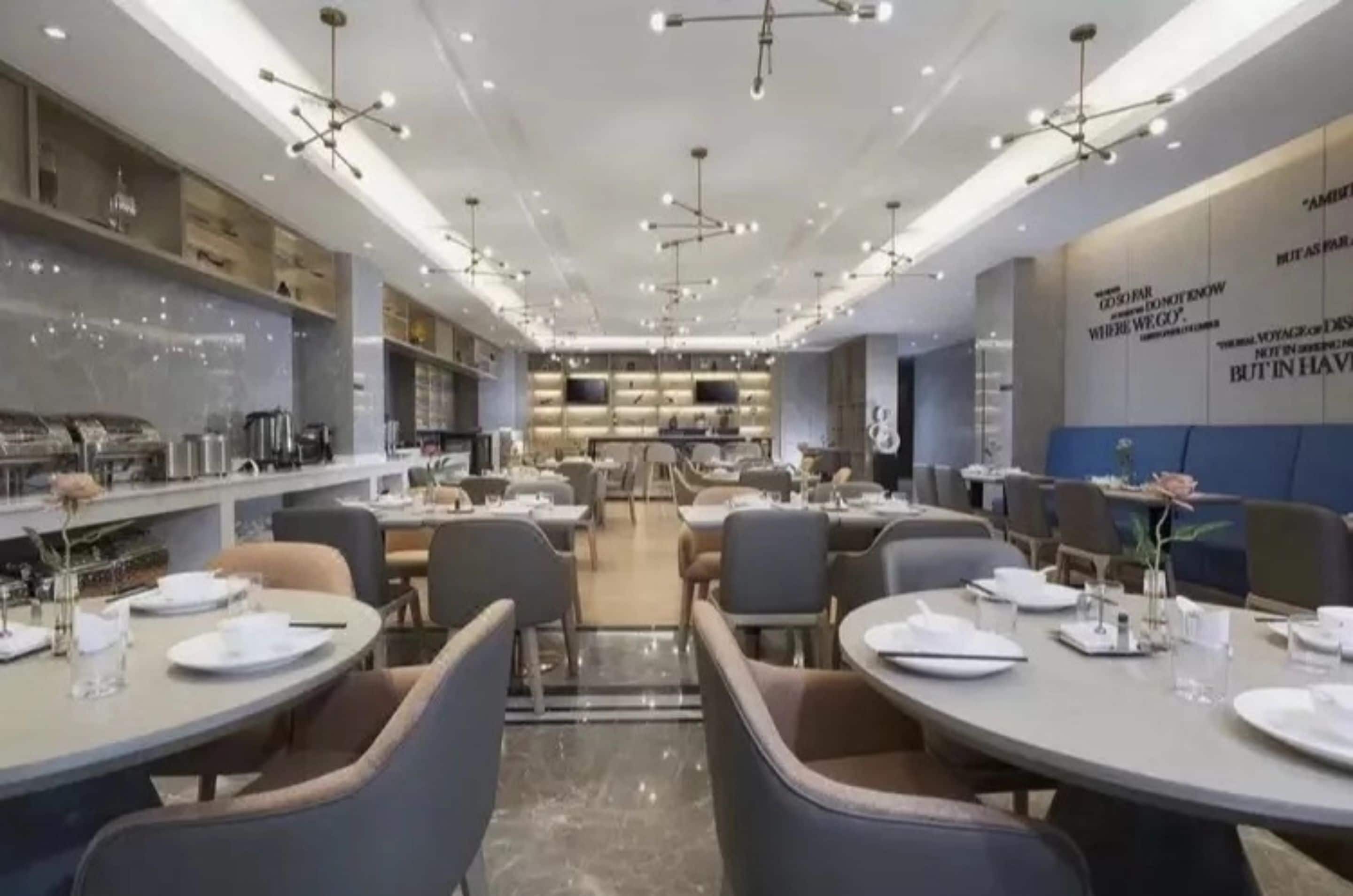 Un comedor moderno con mesas redondas, sillas e iluminación colgante.