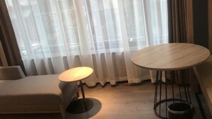 A modern living room with a sofa, a round wooden table, and a small side table. - Naive S Hotel (Shenzhen)