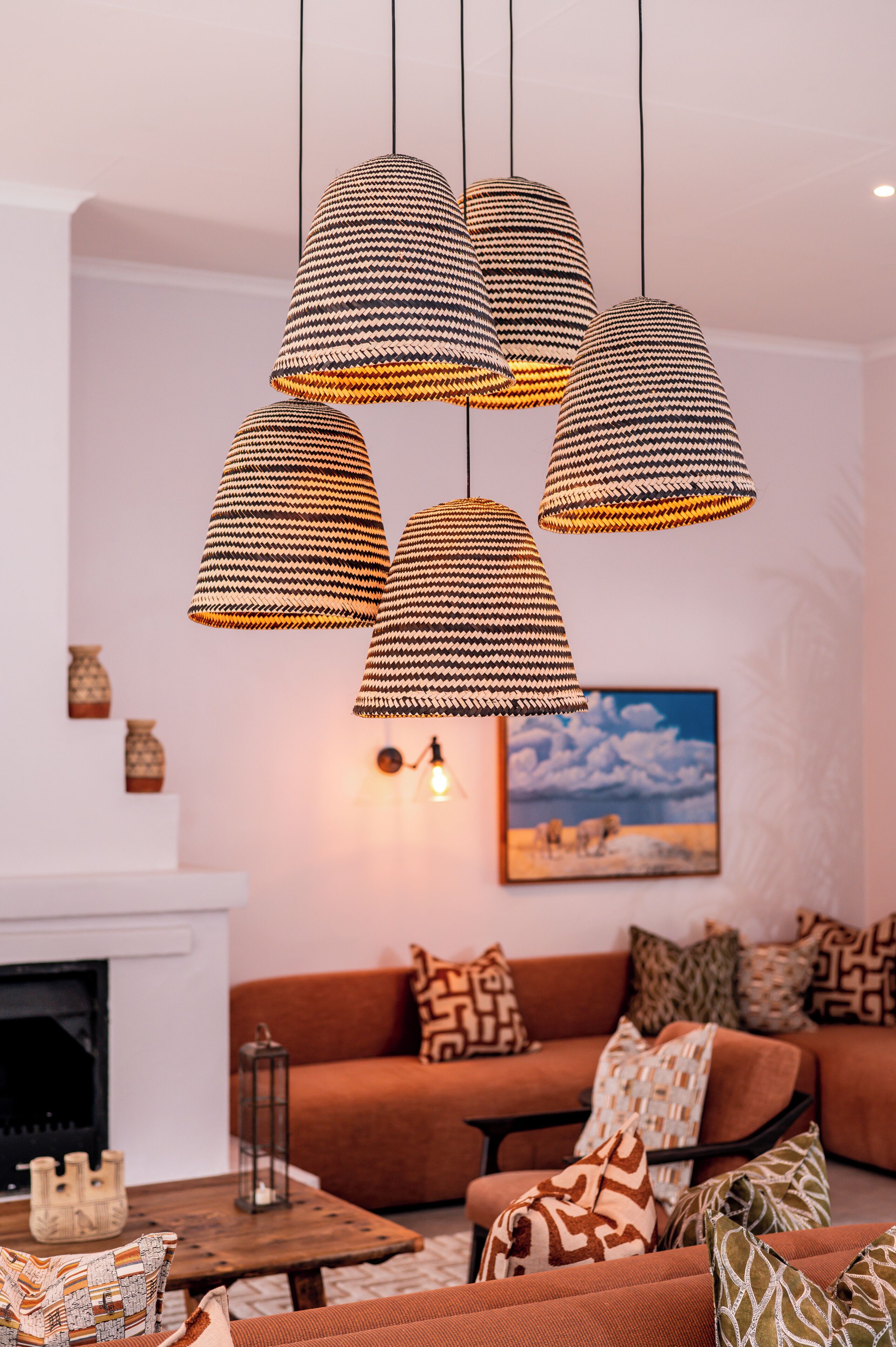 A living room with a sofa, patterned cushions, a fireplace, and hanging lamps.