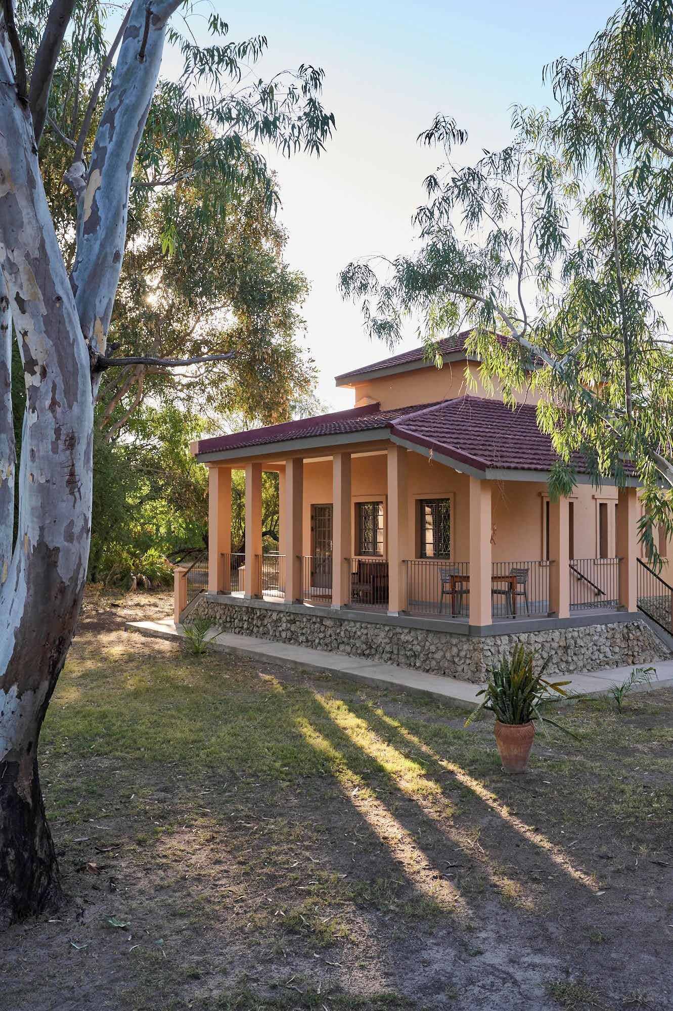 A two-story house with a tiled roof, a covered porch, and a stone foundation.