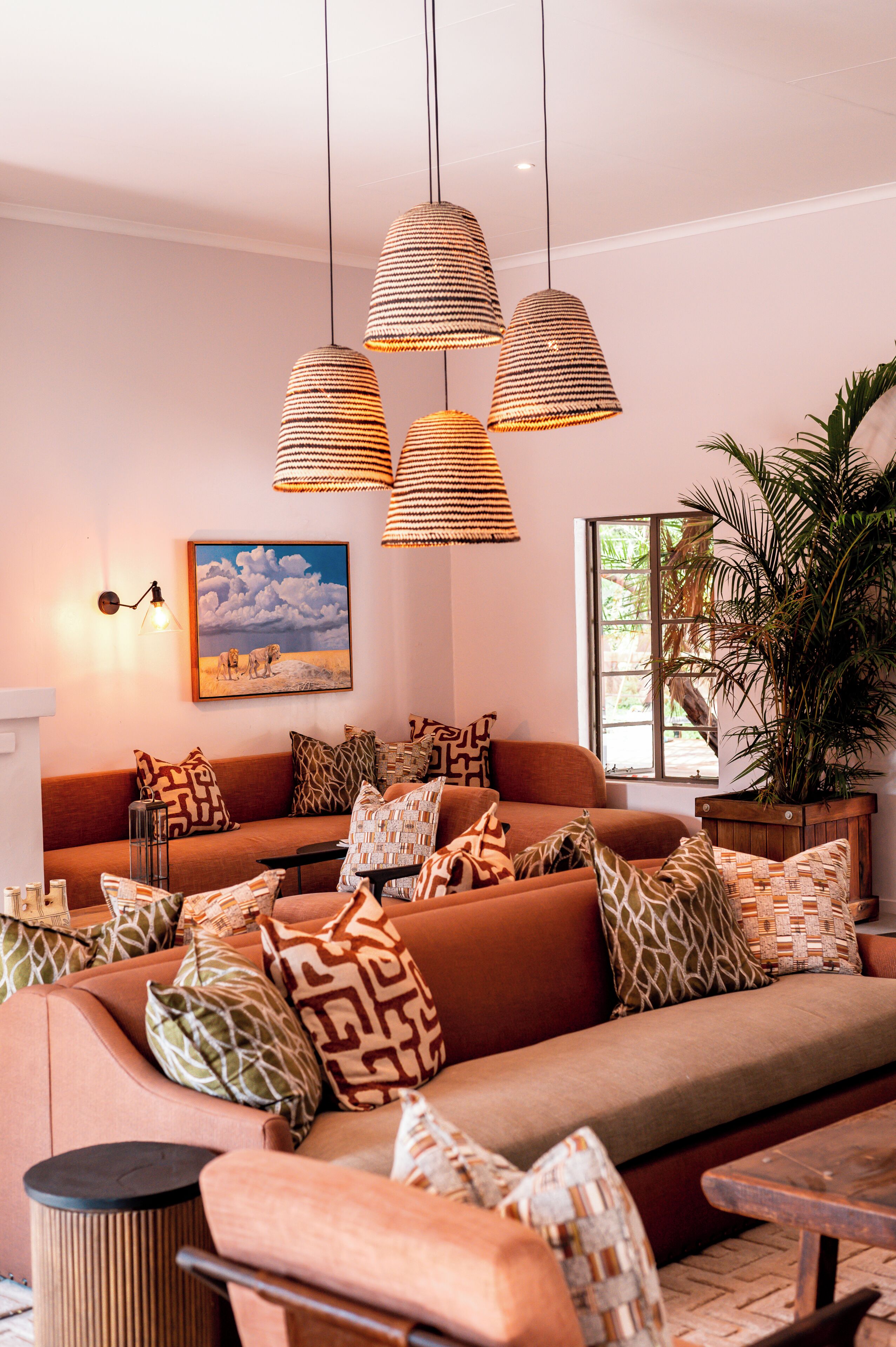 Una sala acogedora con sofá, cojines estampados, un cuadro y una planta en maceta.
