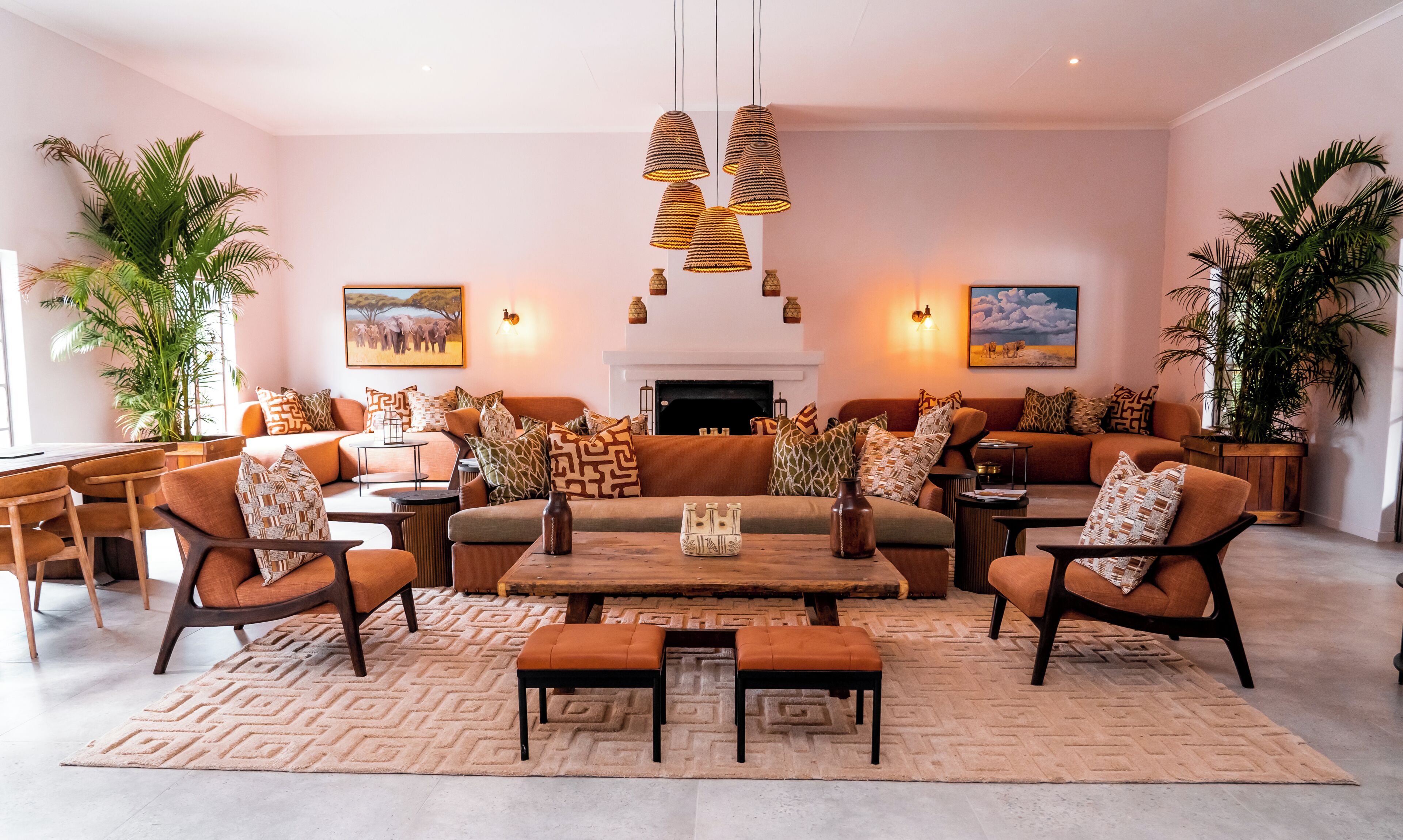 Un salon avec une cheminée, des canapés, des fauteuils, une table basse et des coussins décoratifs.