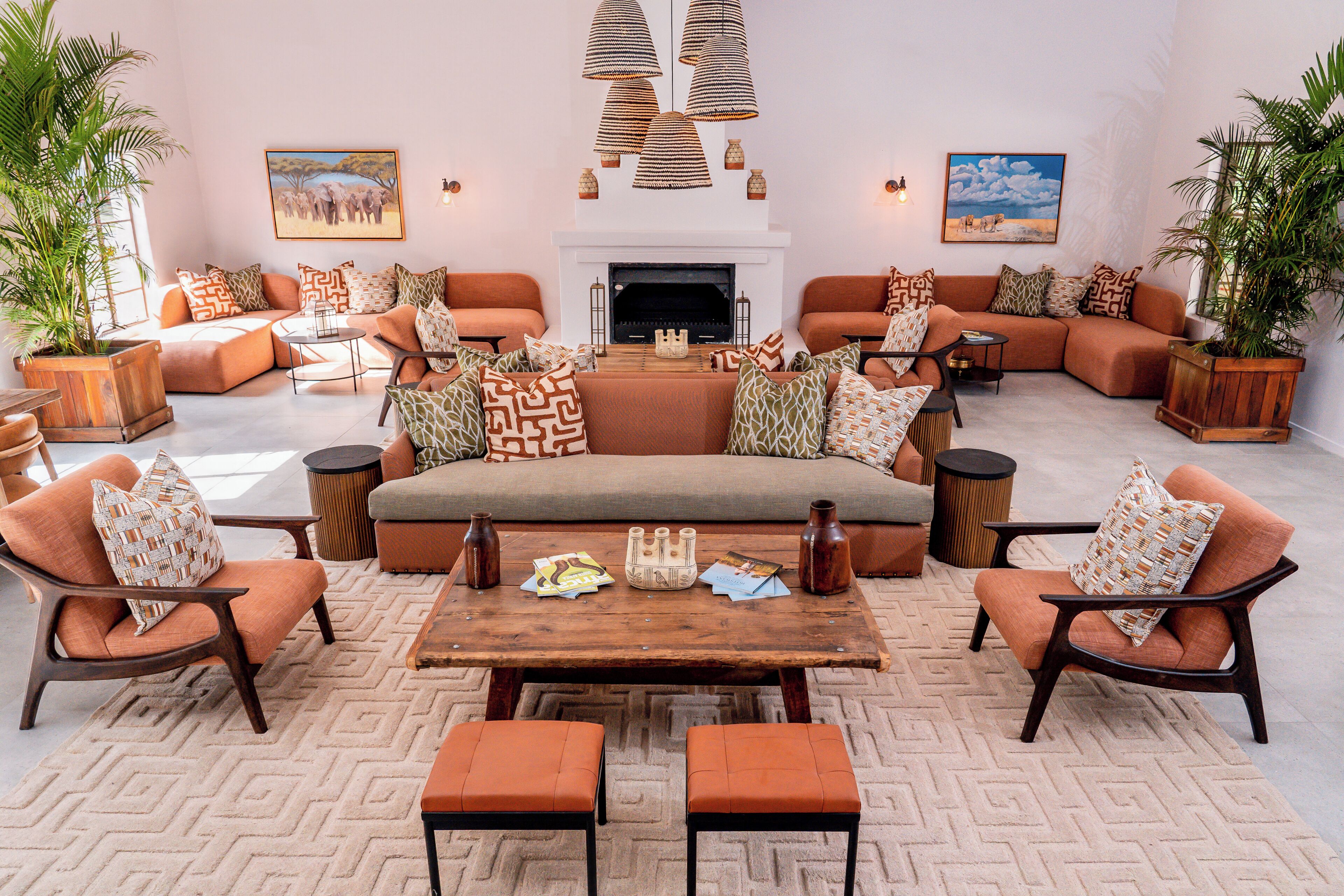 A spacious living room with a fireplace, multiple seating areas, and decorative plants.