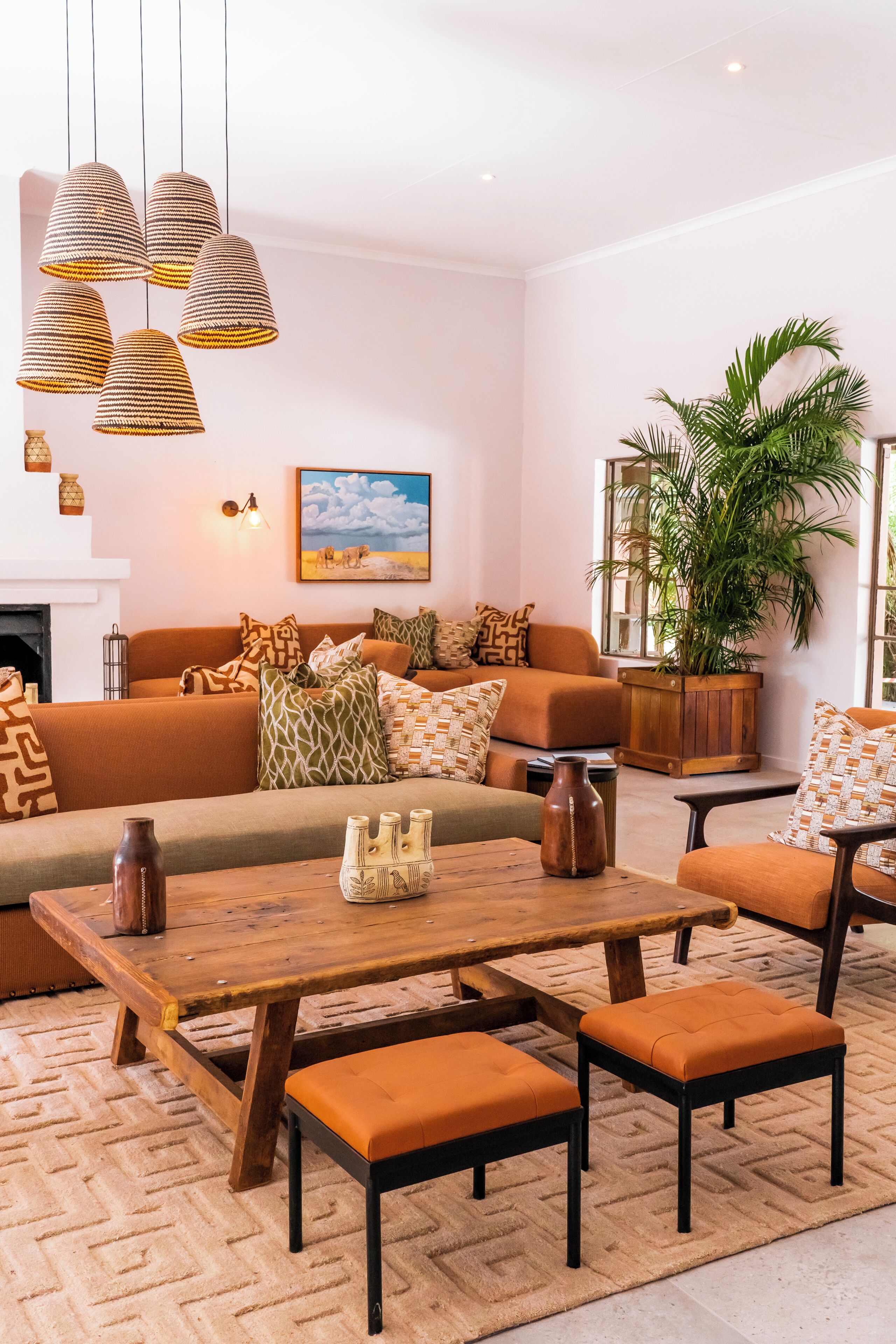 Ein Wohnzimmer mit einer Couch, Poufs, einem Holztisch und Hängeleuchten.