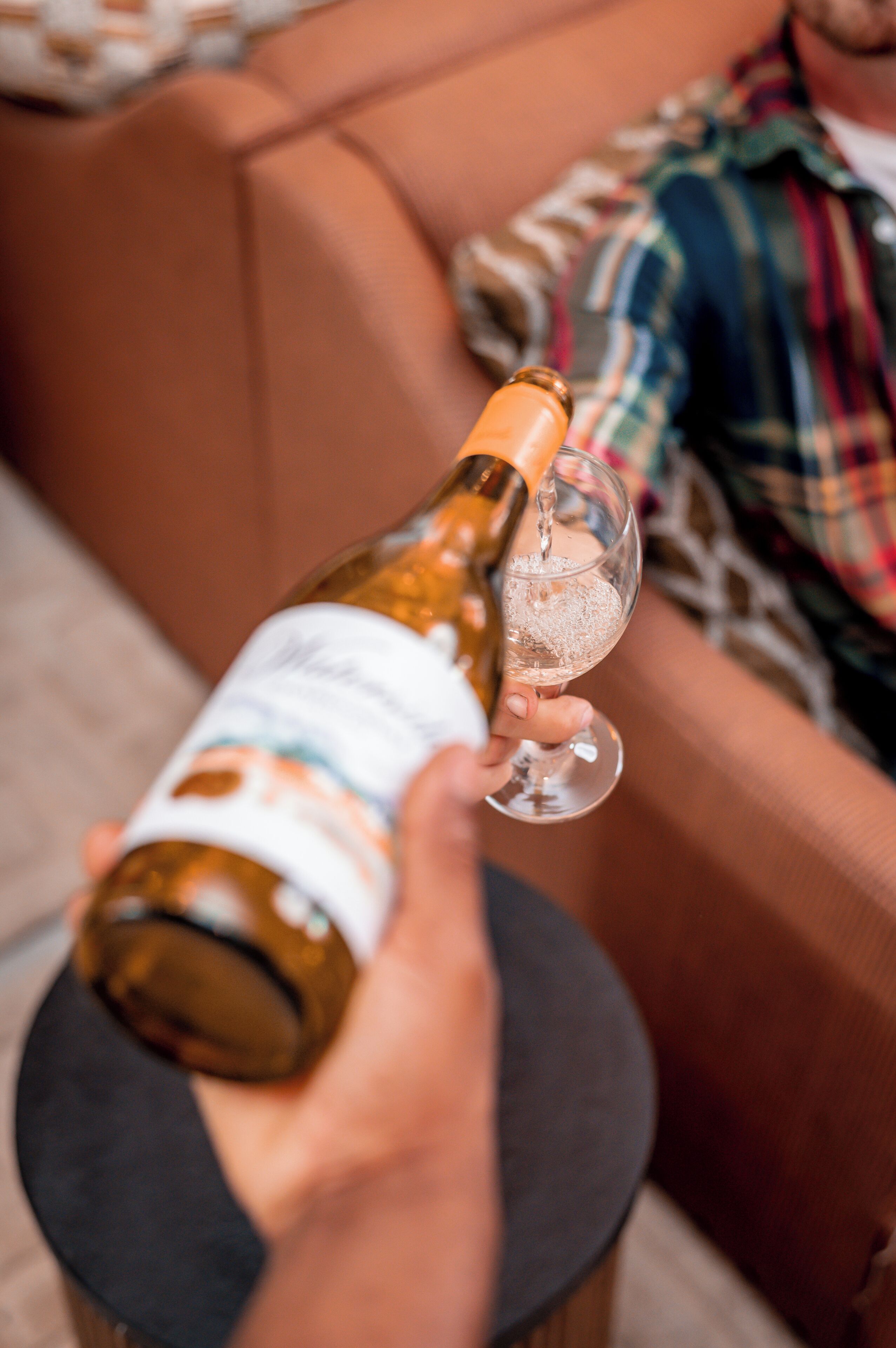 A person pouring a drink from a bottle into a glass.