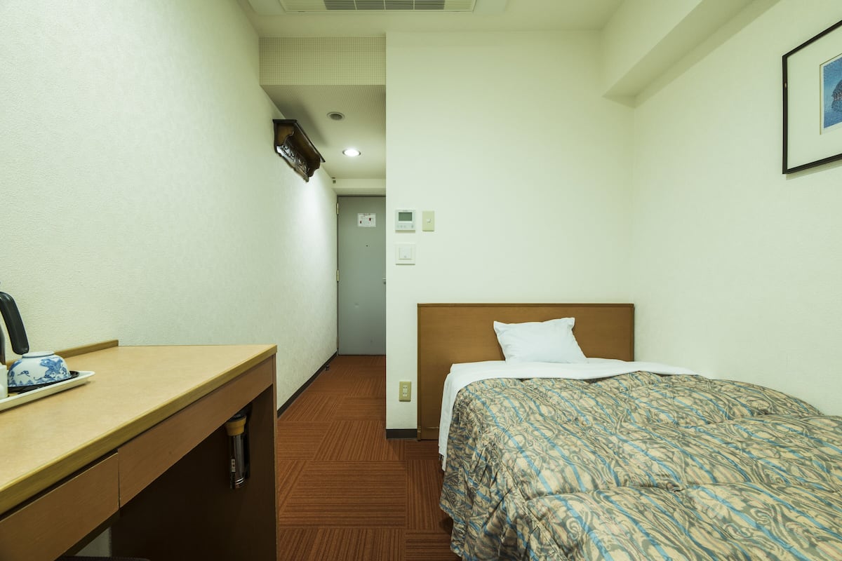 A hotel room with a bed, a desk, and a chair.