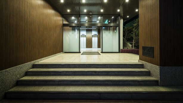 Entrada de un edificio moderno con una escalera que conduce a una puerta de vidrio.
