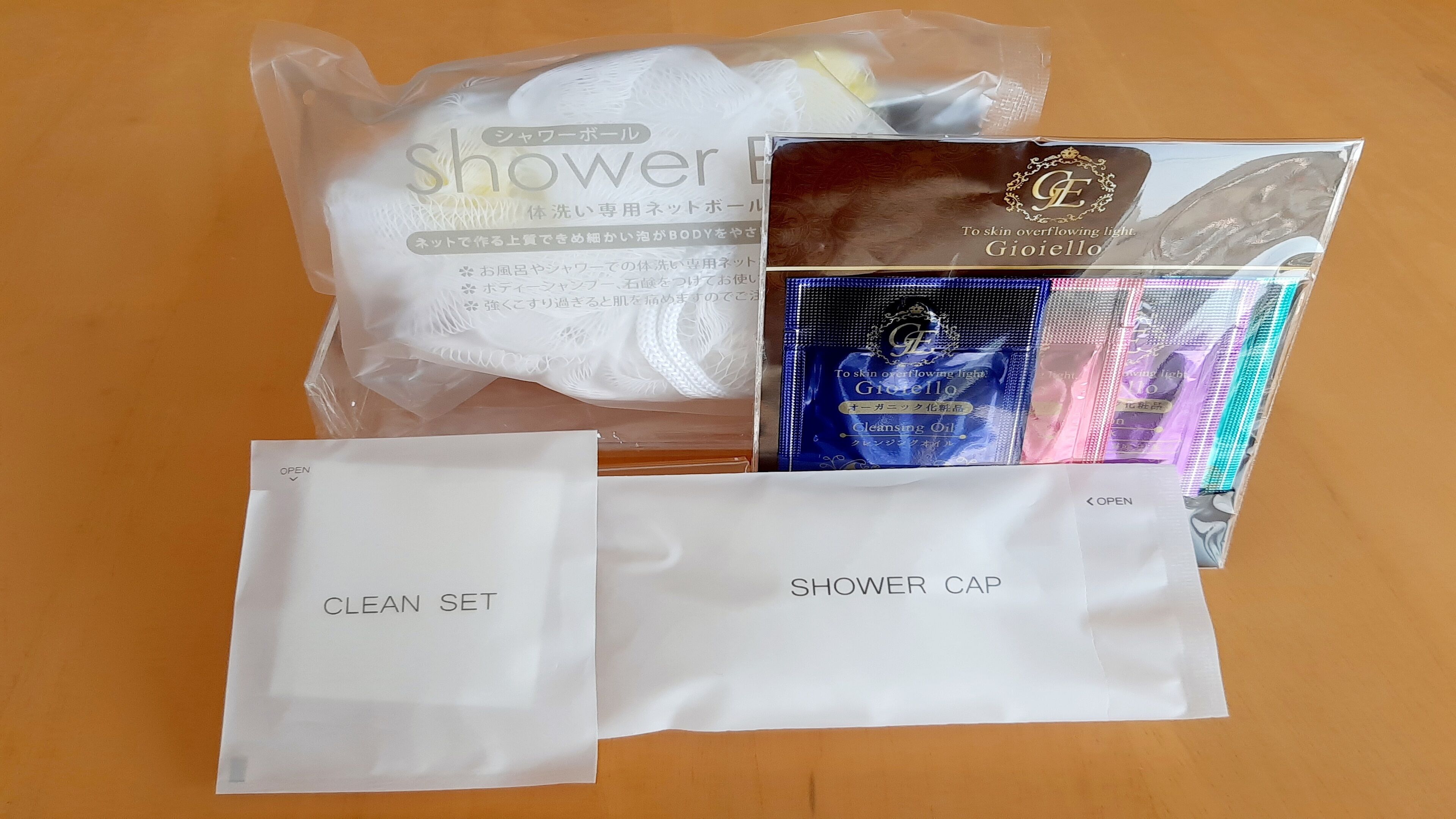 A shower cap, a clean set, and a package of cleansing oil on a wooden surface.