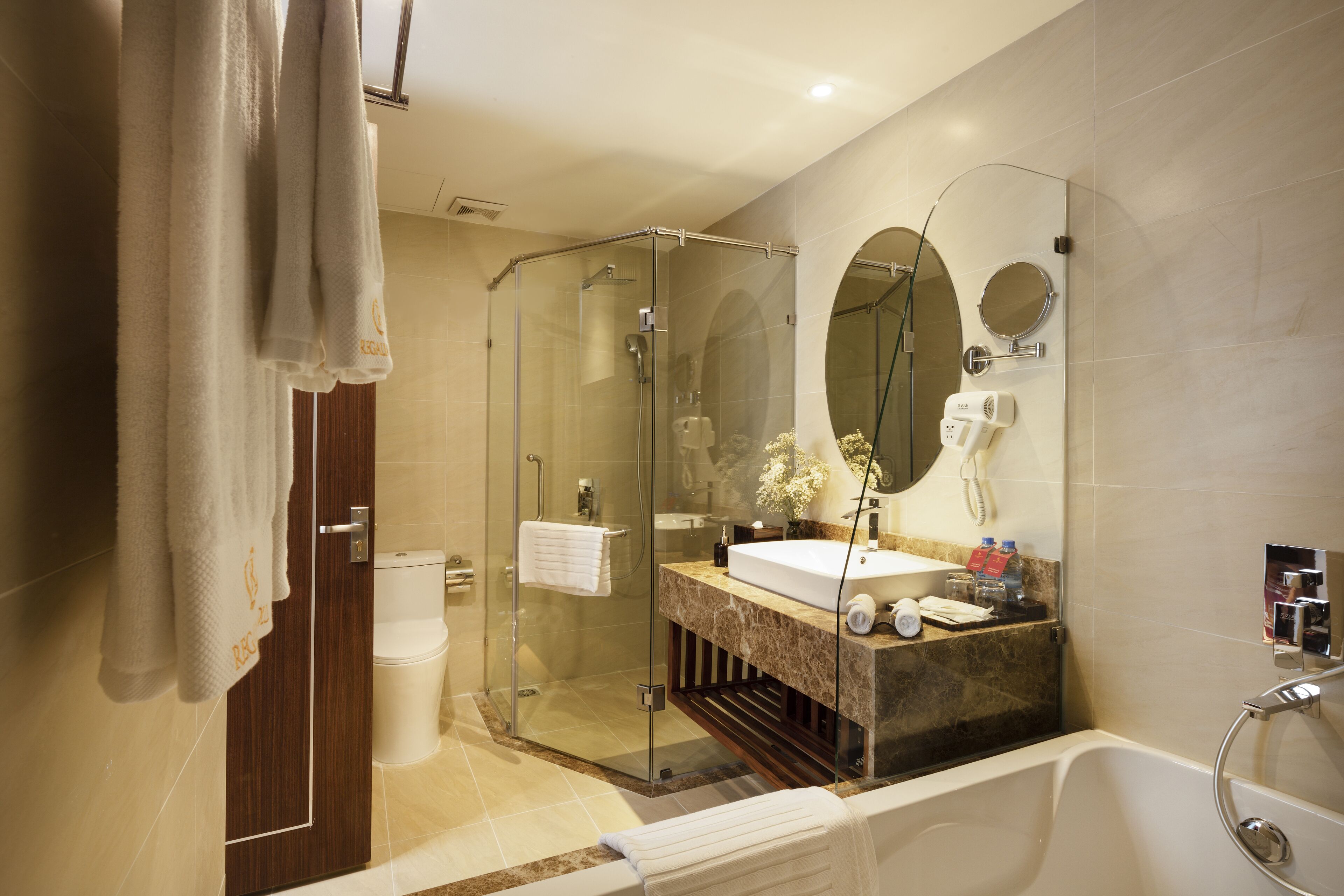 Un baño moderno con ducha de vidrio, lavamanos de mármol y bañera independiente.