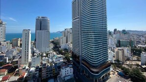Um edifício alto com fachada curva, cercado por outros prédios altos e um céu azul claro.