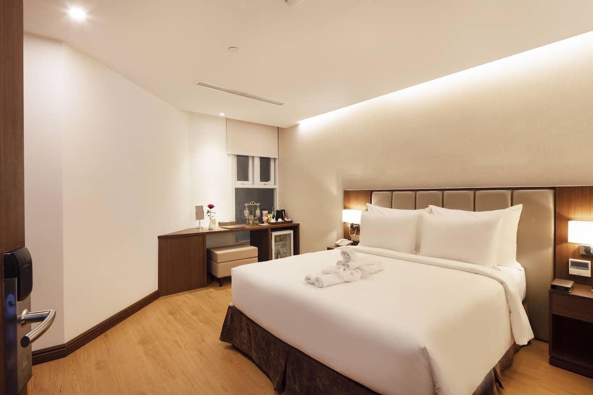 Habitación de hotel con una cama grande, un escritorio con computadora, un minibar y un televisor.