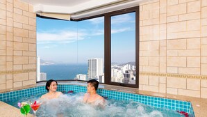 Um casal em uma banheira de hidromassagem com vista para a cidade.